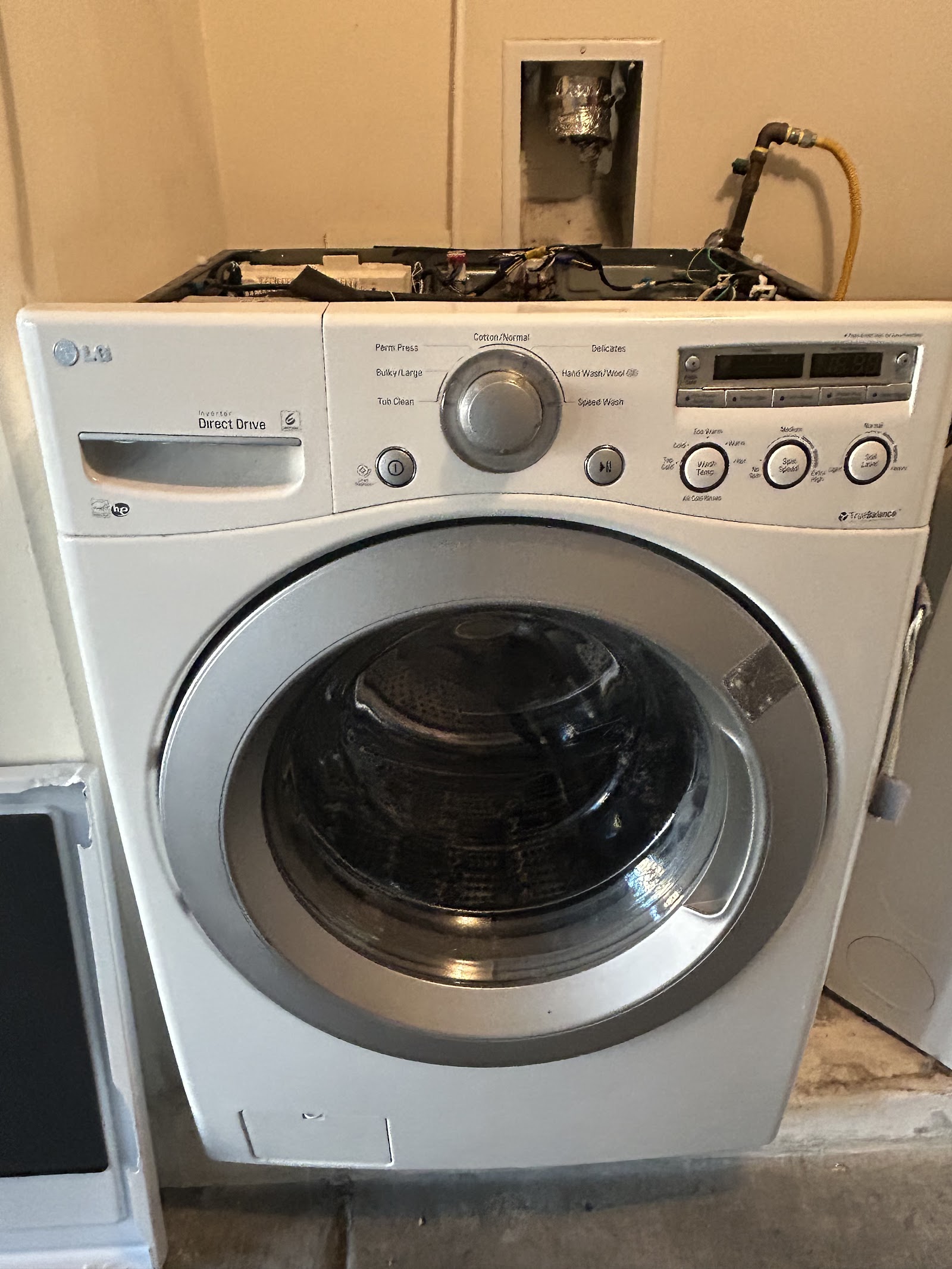 LG front-load washer with the top panel removed, exposing internal wiring during repair