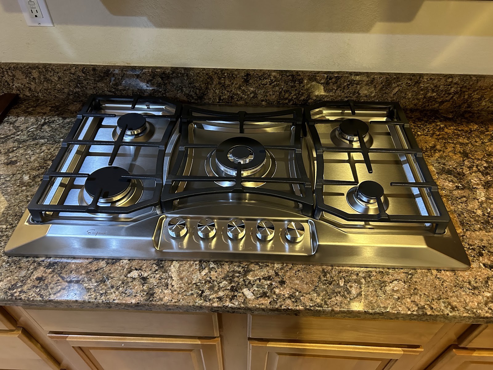 Installed stainless five-burner Empava gas cooktop set in a granite countertop
